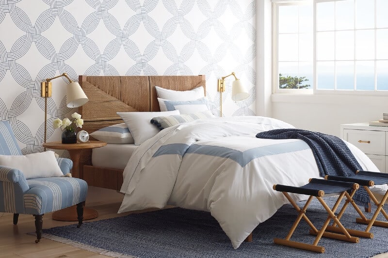 Casual Elegance Coastal Room Designs and Decor Ideas. Carson Collection bedroom set. Shades of Sea and Sky Bedroom collection from Serena and Lily. Muted blue and gray tones. Bedding, Wicker headboard, light blue and white striped accent chair. (affiliate link) https://fave.co/31h2y0h