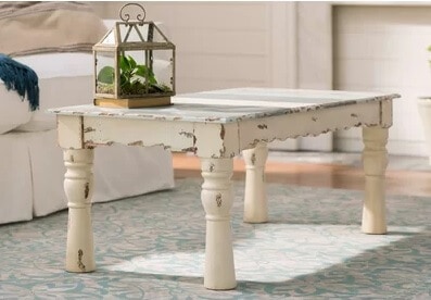 Shabby elegance style meets farmhouse heirloom.  Highly distressed painted coffee table boasts turned legs, a scalloped apron and a touches of beach cottage blue on the table top.
